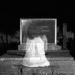 A ghostly woman sitting at her own grave.