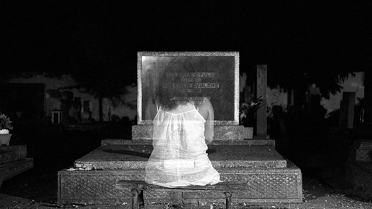 A ghostly woman sitting at her own grave.